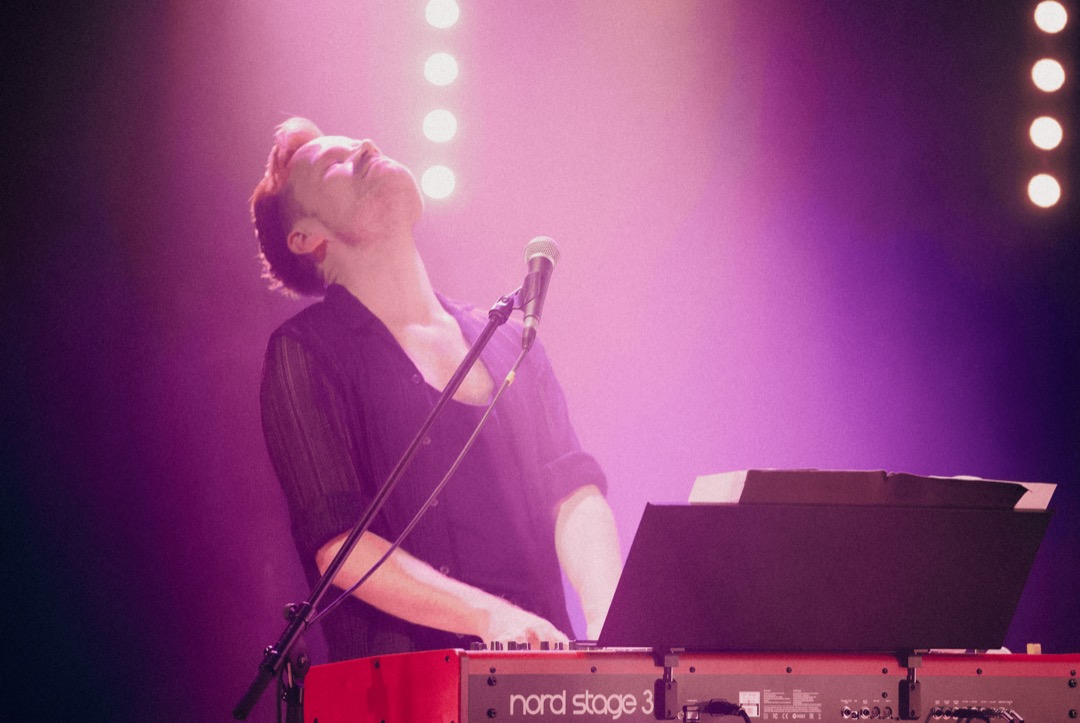 Daisy Steinway singt am Keyboard, in violettes Bühnenlicht getaucht.